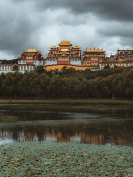 View of the golden-roofed Songzanlin Monastery rising majestically above dark waters under a brooding sky, Di Qing Zang Zu Zi Zhi Zhou, Yun Nan Sheng, China.