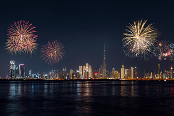 Night panorama of Dubai Downtown from Dubai Creek Harbour, vibrant city lights and colorful fireworks in the sky celebrating the New Year