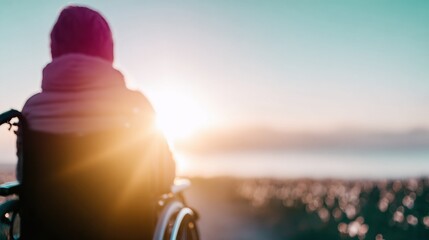 Person in wheelchair watching sunset by the ocean at a calm shoreline