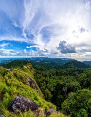 Naklejka premium Lush green hills meet a cloudy blue sky at the horizon