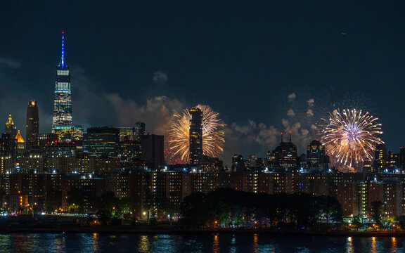 July 4th. View of vibrant fireworks illuminating the night sky over the dark waters, contrasting with the gleaming city skyline, celebrating the 4th of July, New York, New York, United States.