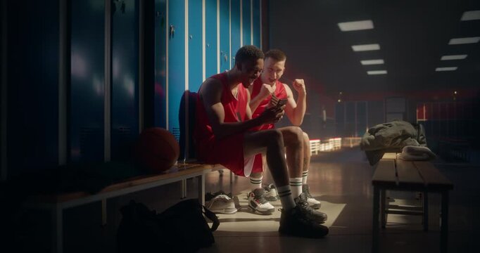 Two Basketball Teammates Sitting Side by Side, Focused on a Mobile Phone. Suddenly They Cheer Loudly, Celebrating Victory and Expressing Excitement Over What They See on Screen or a Winning Bet