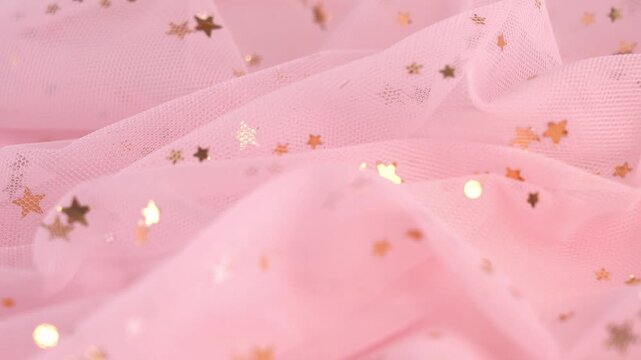 Pink tulle fabric with gold glitters. Textile material tissue cloth background. Texture fabric close up