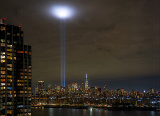 View of Tribute in Light piercing the night sky, illuminating the skyline and dark waters below in solemn remembrance of 9-11, New York, New York, United States.