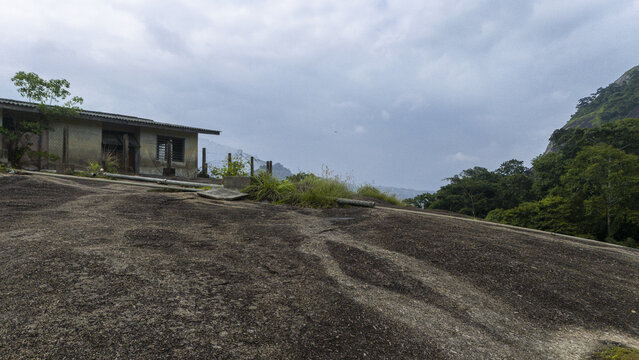 Aerial view of a building sits atop a vast, smooth rock formation, contrasting with the lush greenery and cloudy sky, Ida really, Ondo, Nigeria.