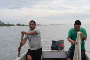 Fishermen preparing nets and rowing boat on sea