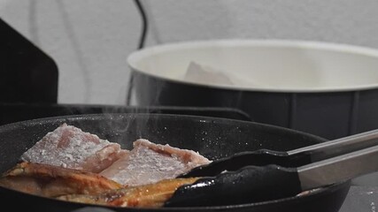 Cooking Delicious Meat in a Frying Pan with Tongs is a staple skill for any aspiring chef Delicious crispy meat is frying in a pan, with tongs in action, making it perfect for cooking enthusiasts ever