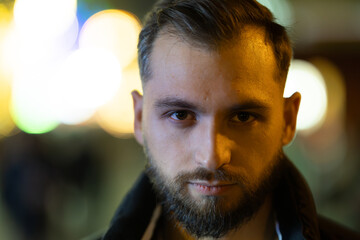 Fototapeta premium Young bearded man gazing directly at urban night