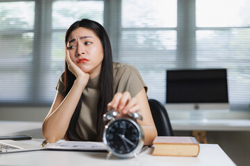 Young woman feeling tired and turning off alarm clock