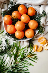 Cozy Christmas arrangement with tangerines on a plate and Christmas tree branches
