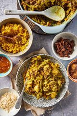 Traditional South African bobotie served with yellow rice, chutney, raisins, and almonds. Overhead view of a spiced ground meat and vegetable casserole, a classic Cape Malay dish, styled with side dis