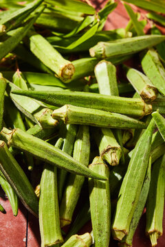 Close-up of fresh green okra pods, also known as lady&rsquo;s finger or gumbo, displayed on a rustic surface.