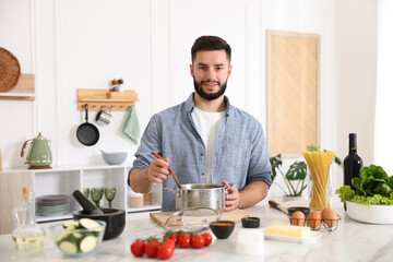 Smiling man cooking at table in kitchen