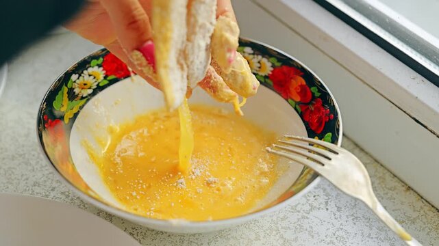 Close up of woman preparing pollock schnitzels dipping flour coated fish in egg