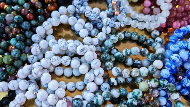 Close-up of colorful handmade bracelets made from a variety of natural stone beads displayed as a collection - push in