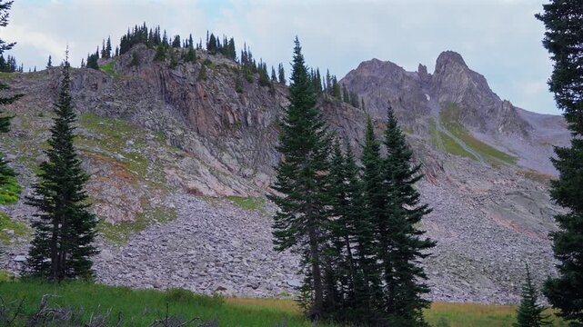 Capitol Peak wilderness camping campsite Mt Daly sunset dusk Colorado summer Aspen Snowmass last light Rocky Mountains Elk Range trailhead hiking high elevation clouds trees above treeline pan left