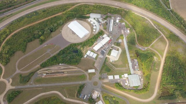 Aerial view of the Millbrook Proving Ground, a vehicle testing centre, showing its tracks and test facilities surrounded by green vegetation, Bedford, England, United Kingdom.