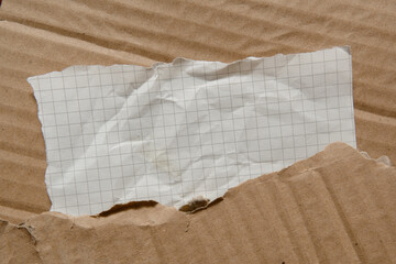 Sloppily torn rectangular-shaped graph paper on a cardboard texture