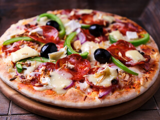 Pizza with chorizo ​​sausage, mozzarella cheese, green pepper and black olives. Rustic wooden background. Soft focus.	