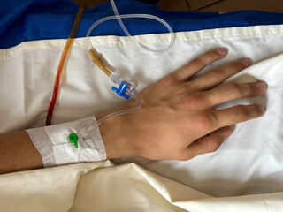 hand on hospital bed with white sheet