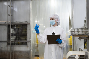 Factory worker working in canned fish factory production line, checking quality of fresh fish while...