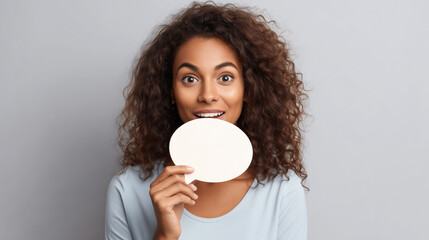 Surprised young woman holding blank speech bubble communication