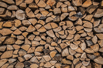 Felülnézeti fotó egy rendezett fahasáb-kupacról. A természetes anyag, a fa mintázata és textúrája különleges geometriai mintát alkot a kompozícióban.