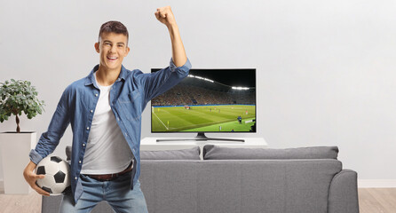 Happy young man in a living room holding a football