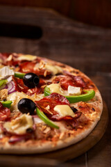 Pizza with chorizo ​​sausage, mozzarella cheese, green pepper and black olives. Rustic wooden background. Soft focus.	