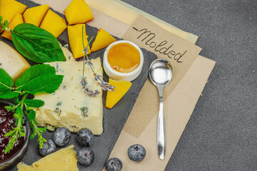 Cheese platter with Tete de Moine, assorted cheeses, fruits, jam and herbs on a slate board