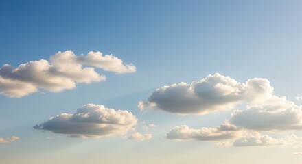 A bright sky with soft white clouds scattered across a blue background. The clouds are fluffy and partially cover the sky, creating a calm and natural atmosphere