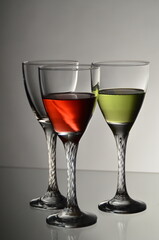Three Elegant Wine Glasses with Red and Green Drinks on Neutral Background