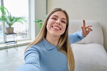 Selfie portrait happy beautiful young woman in home interior