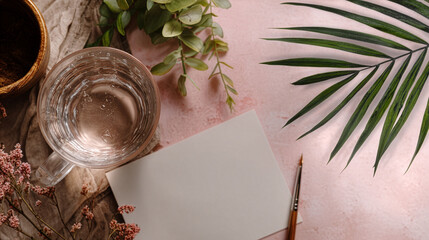 Natural Workspace with Water, Greenery, and Blank Card on Pink