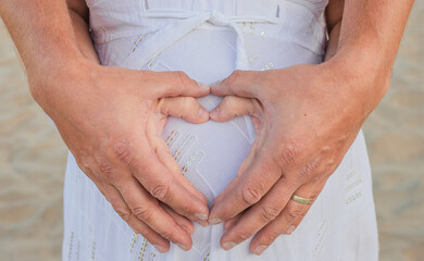 Couple's hands making a heart shape, expecting a baby, new arrival, love, motherhood, care, photo for a photo frame
