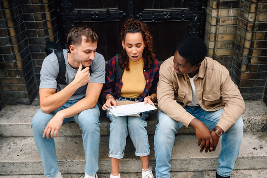 Students reviewing notes sitting on university steps