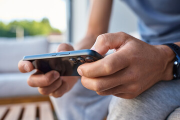 Man using smartphone, close up. Male hands holding smartphone and playing mobile game outdoors. Concept of technology, digital entertainment and gadget using