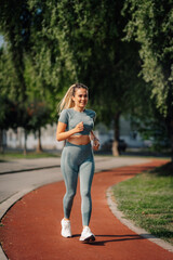 Fototapeta premium Young sporty woman running in a city park