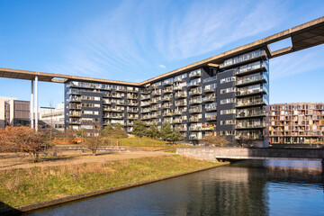 Modern waterfront residential buildings in Orestad Copenhagen with elevated bridge structure and clear blue sky offering strong copy space for corporate branding