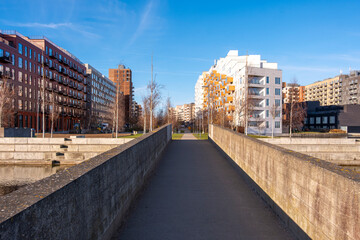 Pedestrian pathway between modern residential buildings in Orestad Copenhagen under bright sky with minimal design and copy space for branding