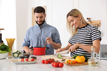 Happy couple cooking together at table in kitchen