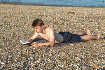 Teenage Boy Reading On A Beach
