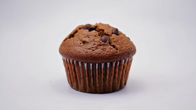 Enjoy a warm, fresh-baked chocolate chip muffin in a bakery or cafe setting, inviting comfort food and sweet indulgence for breakfast or brunch