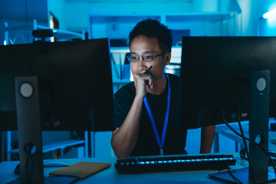 Software engineer analyzing programming language code, focusing on cybersecurity, IT systems, and digital data security in dark office.