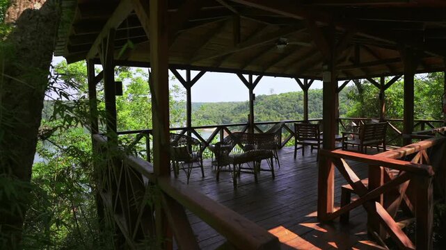 Slow motion reveal of Jungle Cabin Lodge&rsquo;s outdoor dehor shows a wooden deck over the Paran&aacute; River, surrounded by lush jungle in Misiones, Argentina&mdash;blending rustic architecture with natural immersion