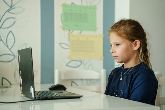 Young schoolgirl stares intently at a computer screen. Illustrating e-learning, distance learning and home schooling. 