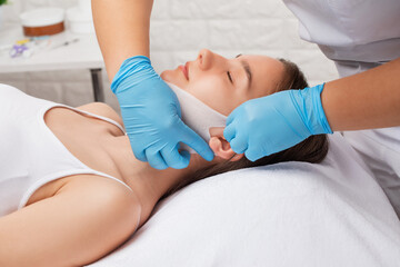 A cosmetologist makes a fat-burning mask for a double chin. Cosmetology and professional skin care.