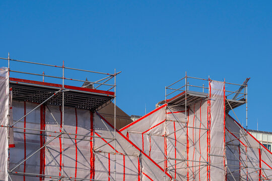 Scaffolding and structures on residential construction site in Hamburg with protective mesh under clear sky providing copy space for corporate branding