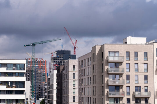 Modern residential buildings in Hamburg under construction with cranes in background showing urban development and real estate progress for branding use