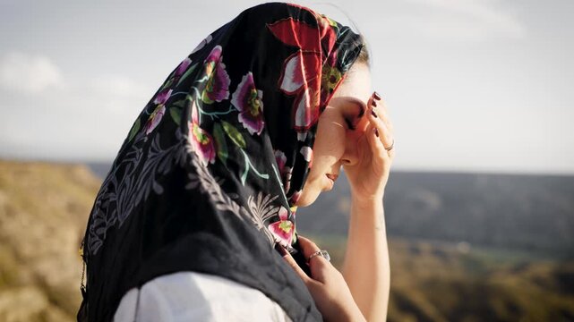 Sad woman meditating and praying on a windy mountain